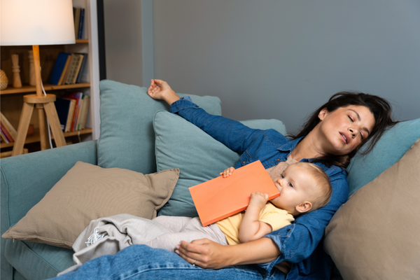 Tired Mom asleep before finishing reading a book to her baby. Maternal depletion