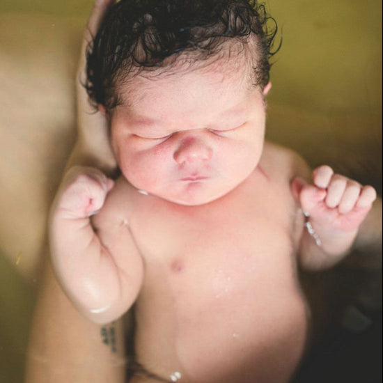 Newborn baby floating peacefully in a warm herbal bath, supported by a parent’s hands. A calming postpartum ritual that nurtures the baby’s delicate skin and promotes bonding. Ideal for content on newborn skincare, natural baby baths, and holistic postpartum care.