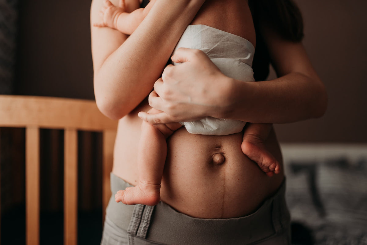 Mother postpartum holding a newborn baby against her chest