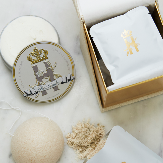 Evening containment ritual by Royal Heir Botanicals is a luxury maternity skincare set for mom and baby featuring a cream coloured cube shaped box for Lavender botanical soak, a round grey and gold tin with First touch whipped organic,EWG verified butter for newborns, konjac sponge with a string and a few white sachets with golden logo on the front with lavender botanical soak on a white marble surface